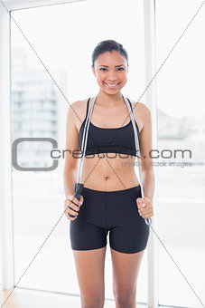 Content dark haired model in sportswear holding a skipping rope
