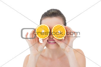 Playful natural brown haired model hiding her eyes behind orange halves