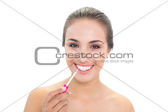 Cheerful brunette woman applying lip gloss