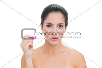 Stern bare brunette holding lip gloss