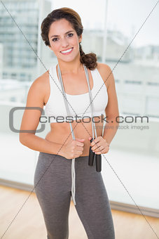 Sporty happy brunette holding skipping rope
