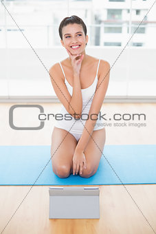Pleased natural brown haired woman in white sportswear posing looking away
