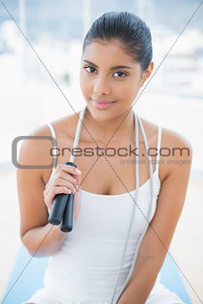 Content toned brunette sitting on floor with skipping rope