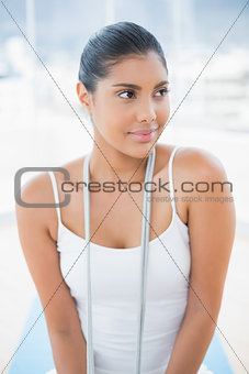 Peaceful toned brunette sitting on floor with skipping rope