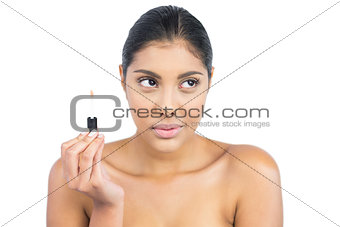 Serious nude brunette holding lip gloss