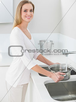 Happy gorgeous woman filling pan with water