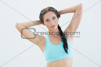Fit young woman standing with hands behind head