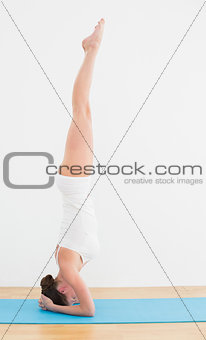 Side view of a woman standing upside down on exercise mat