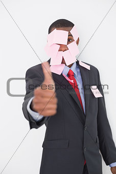 Afro businessman covered in blank notes gesturing thumbs up