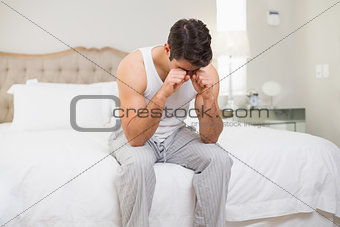 Young man rubbing his eyes in bed