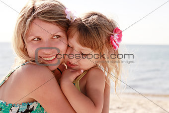 Mama and her little daughter playing on the beach