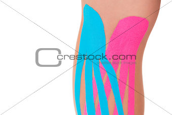 Close up of patients knee with applied pink and blue kinesio tape