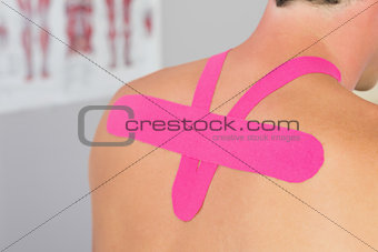 Close up of male patients back with applied pink kinesio tape