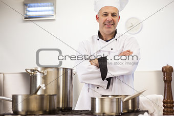 Smiling head chef standing arms crossed behind pot