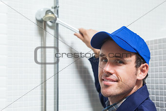 Cheerful plumber repairing shower head
