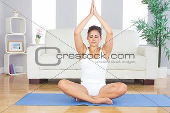 Slim brunette woman relaxing sitting in lotus position on exercise mat