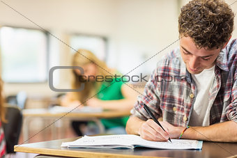 Student with others writing notes in classroom
