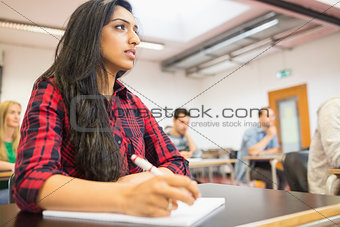 Semale student with others writing notes in classroom