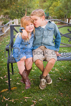 Happy Young Brother and Sister Sitting Together Outside