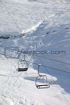 Two chair-lift with snowdrift and off-piste slope in sun morning