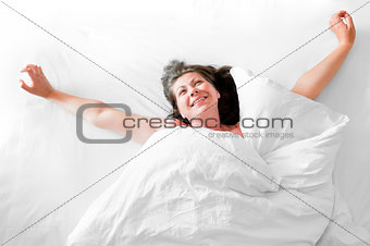 Photo of a young woman waking up happy with a morning stretch