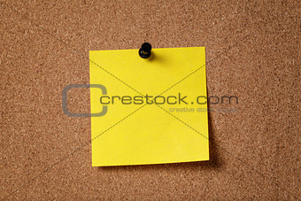 yellow reminder sticky note on cork board