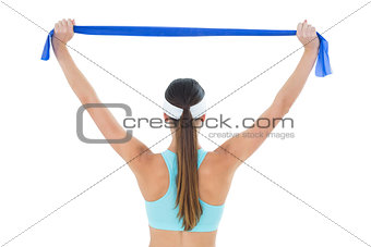 Rear view of a fit woman holding up a yoga belt