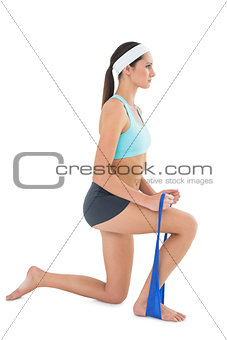 Fit young woman exercising with a blue yoga belt