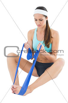 Full length of a fit woman with a blue yoga belt