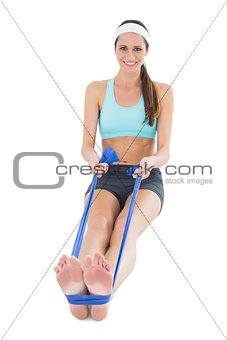 Smiling fit woman exercising with a blue yoga belt