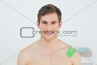 Handsome young man with green kinesio tape on shoulder