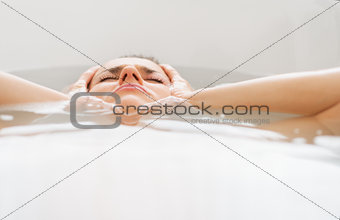 Stressed young woman laying in bathtub