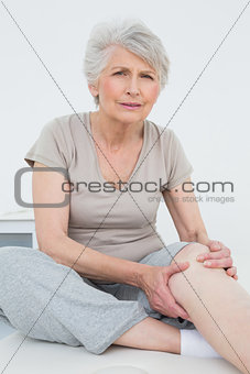 Senior woman with painful knee sitting on examination table