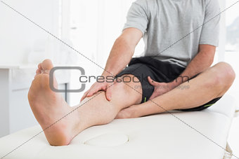Low section of a man with hands on a painful leg