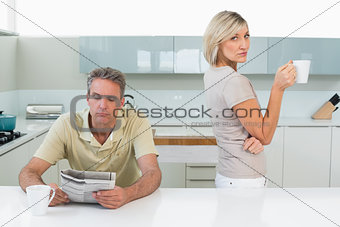 Man reading newspaper and woman with coffee cup