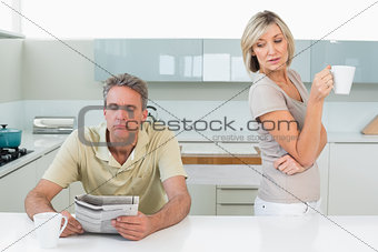 Man reading newspaper and woman with coffee cup