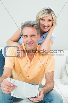 Happy couple reading newspaper at home