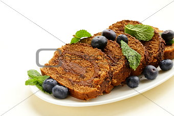 chocolate biscuit roll garnished with mint leaves and blueberries