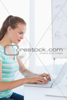Casual woman using laptop at a bright office