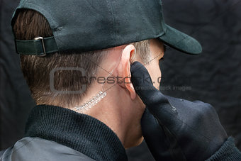 Security Guard Listens To Earpiece, Over Shoulder
