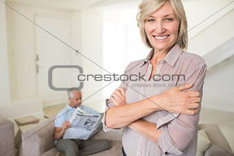 Smiling woman with man reading newspaper at home