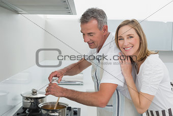 Side view of a happy couple preparing food in kitchen