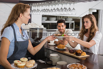 Cafe owner giving sandwich to a woman at coffee shop