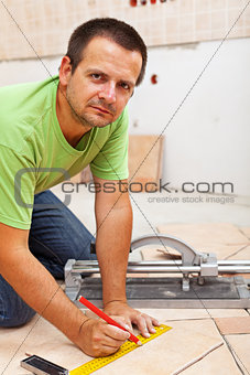 Man marking and cutting ceramic floor tiles