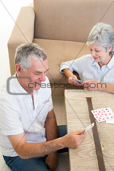Senior couple sitting on floor playing cards