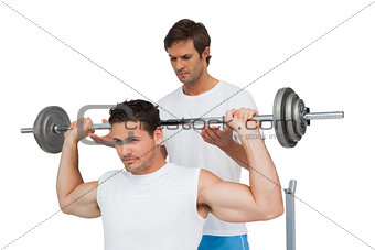 Trainer helping fit man to lift the barbell bench press