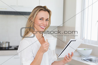 Smiling woman holding mug and newspaper
