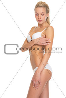 Portrait of young woman in lingerie checking skin condition