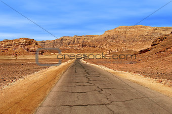 Paved road through Arava desert among red mountains in Timna national park, Israel.