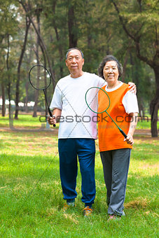 smiling older sibling and sister holding badminton racket 